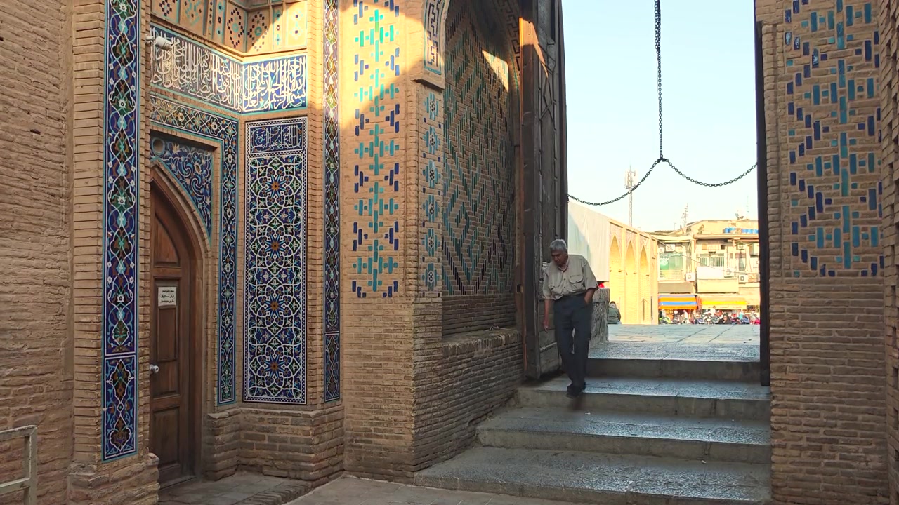Tarihi cami girişinin merdivenlerinden inen yaşlı adam.