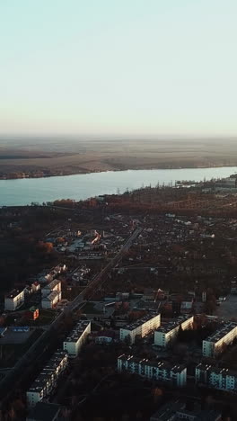 panorama of a small city near the river on the background of a power station in summer. aerial view vertical video