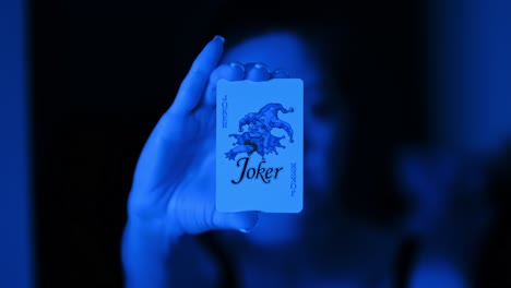 slow motion moment where joker card becomes clear in hand under blue lighting