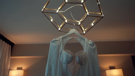 una toma suave hacia atrás de un vestido de novia, colgada en una habitación decorada