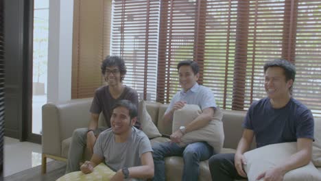 group of asian flat mates watching sports competition on tv at home