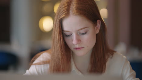 pretty young woman with red hair is working with laptop in apartment portrait of female student