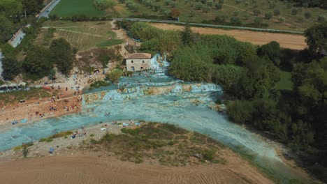 imágenes de drones de las famosas aguas termales saturnia cascate del mulino con su agua azul cálida cerca de grosseto en el idílico paisaje de toscana, italia con gente, campos y olivos alrededor