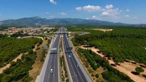 tiro aéreo sobre una intersección de carretera ocupada que lo enrosca a través de campos verdes exuberantes y prados