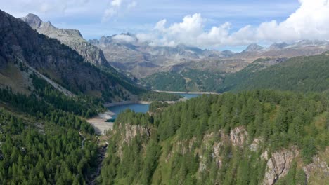 Lago-Di-Devero-En-Alpe-Devero-Con-Frondosos-Bosques-Y-Montañas-Escarpadas,-Vista-Aérea