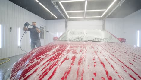 car washing cleaning with foam and high pressured water. red car