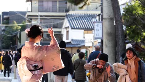 person in kimono waves while walking outdoors