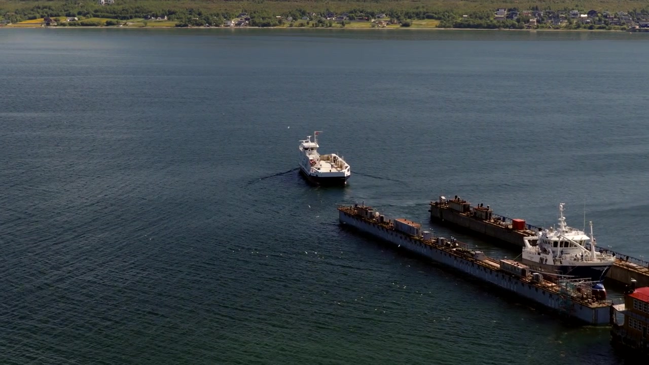 Ship sits beside the Tromso shipyard on a calm Norwegian fjord. Aerial
