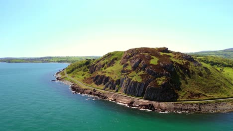 side-on aerial video of a mountain at the causeway coastal route on a bright and sunny day. filmed in ballygally in 4k, 60fps and with rec800 color.