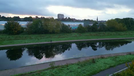ángulo bajo desciende a la orilla de un río tranquilo exe cerca de la estación de tren de exeter st david en otoño con una persona no reconocida en una caminata matutina