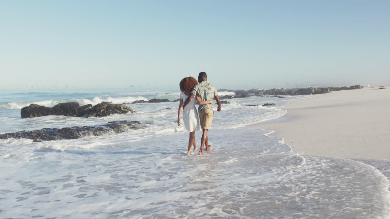 pareja afroamericana caminando por la costa