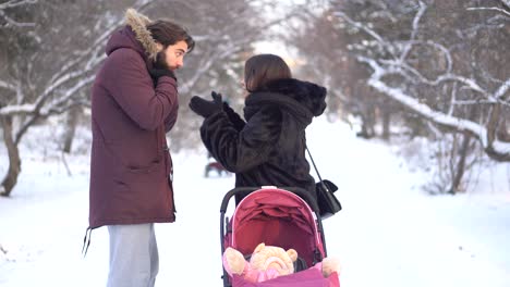 couple with baby stroller in a snowy park