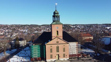 Kongsberg-kirche-Norwegen---Antenne,-Die-Die-Vordere-Fassade-Des-Gebäudes-Zeigt,-Während-Sie-Sich-Nach-Rechts-Bewegt-Und-Sich-Langsam-Dreht,-Während-Die-Kirche-In-Der-Mitte-Bleibt