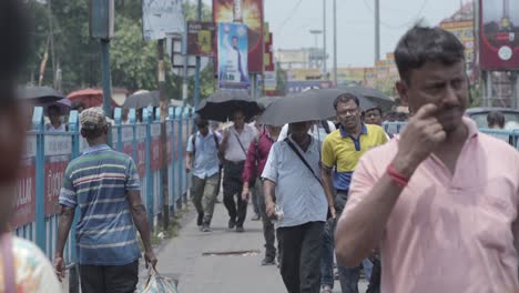 people walking on a busy urban street with umbrellas in india