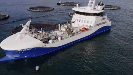 fast drone shot tilting to show the deck of a fish farming well-boat