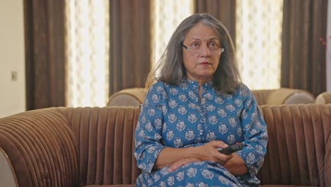 serious aged indian woman watching tv at night