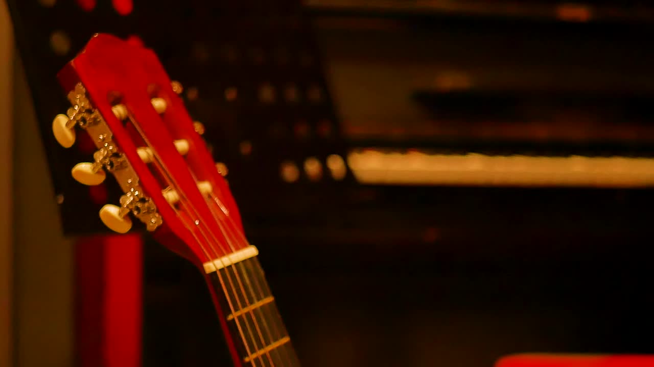 A close-up view focuses on the top part of a guitar, showcasing the intricate details of the instrument. The soundhole, strings, fretboard, and headstock are prominently displayed