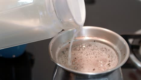 pouring milk in boiling hot chai tea