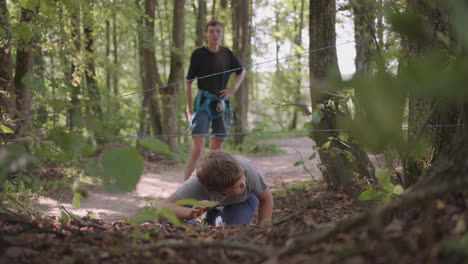 a boy in a summer camp hike overcomes an obstacle by crawling on the ground and tumbling. fun children's challenges