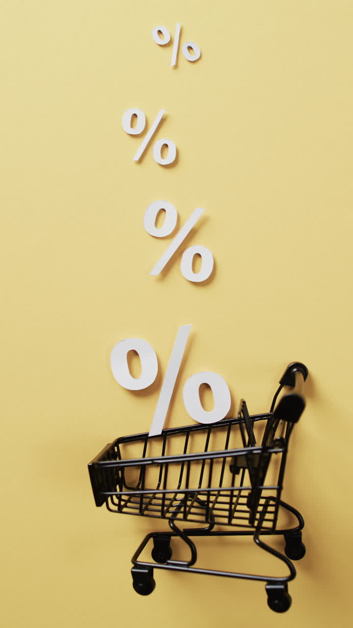 Vertical video of shopping trolley and white percent signs on yellow background