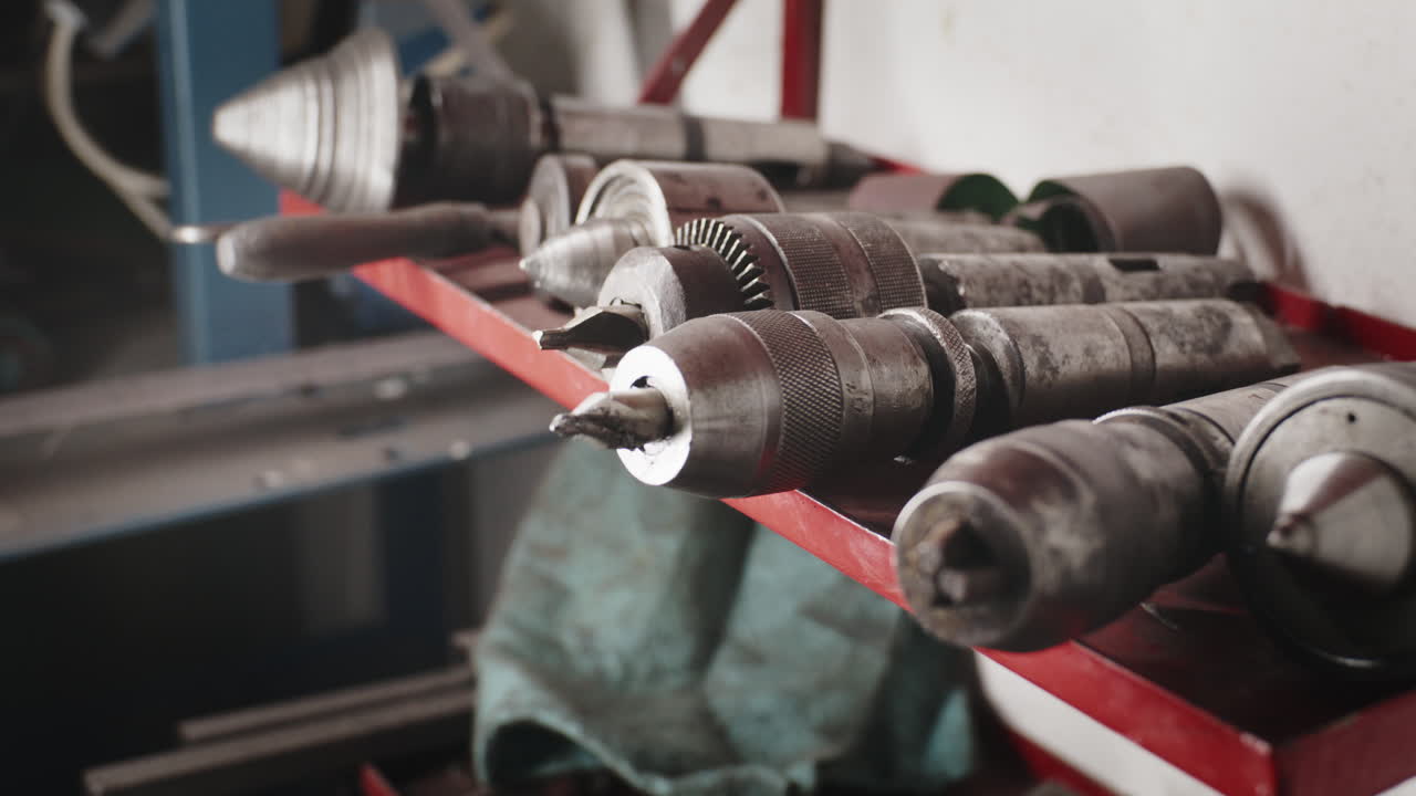 Close-up shot of a steel lathe centers and a drill chuck on a red metal shelf in a machine shop