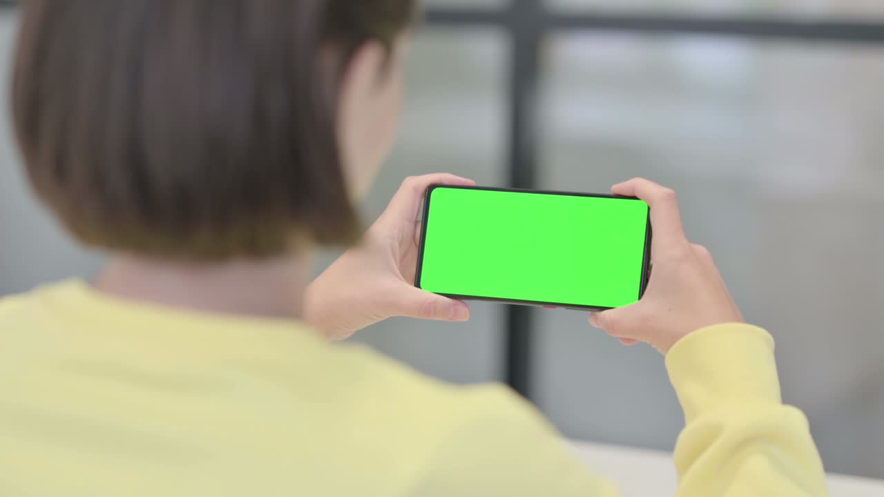 초록색 화면 을 가진 스마트폰 을 보고 있는 여자