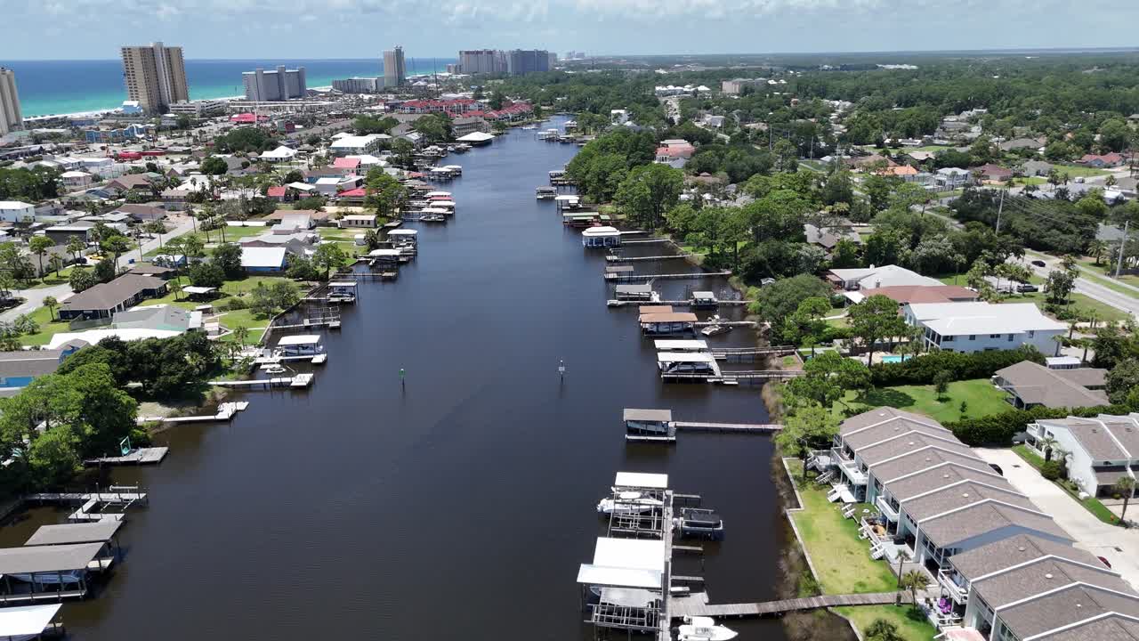 Dynamic backwards drone movement over inland waterway on residential area with docks, Panama City Beach, Florida, USA