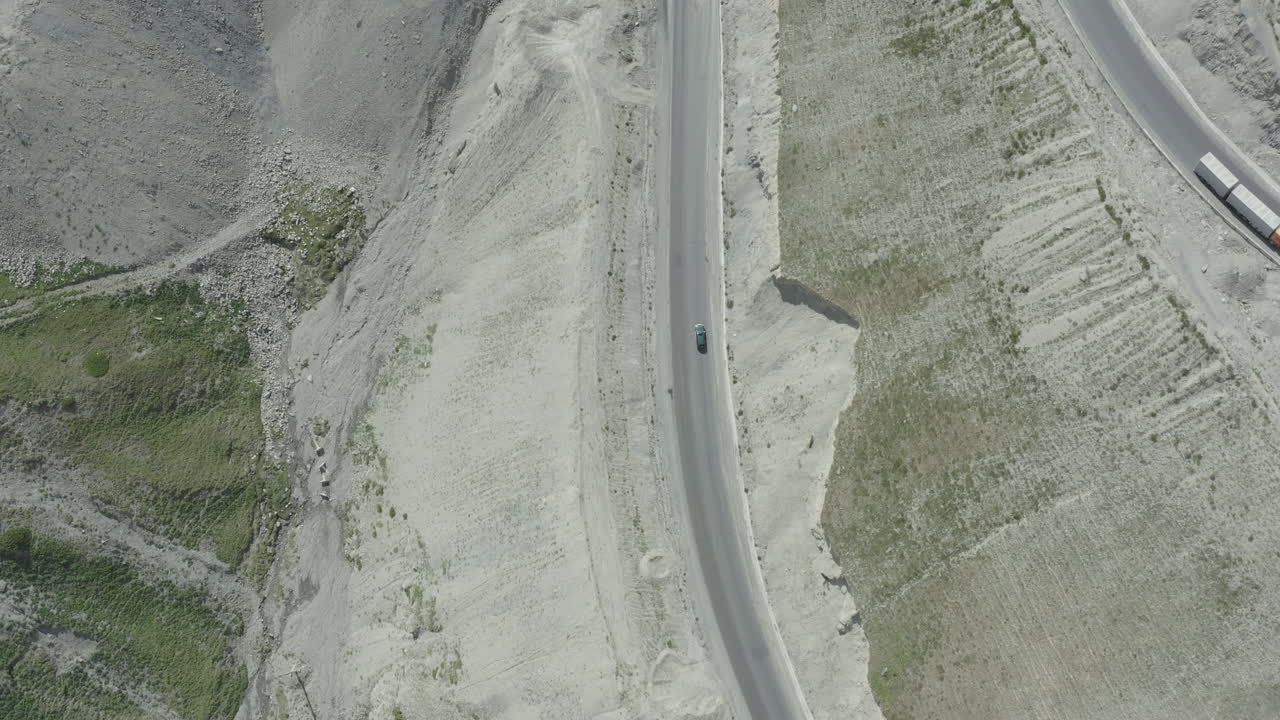 A car on a winding road surrounded by rocky terrain in kyrgyzstan, aerial view