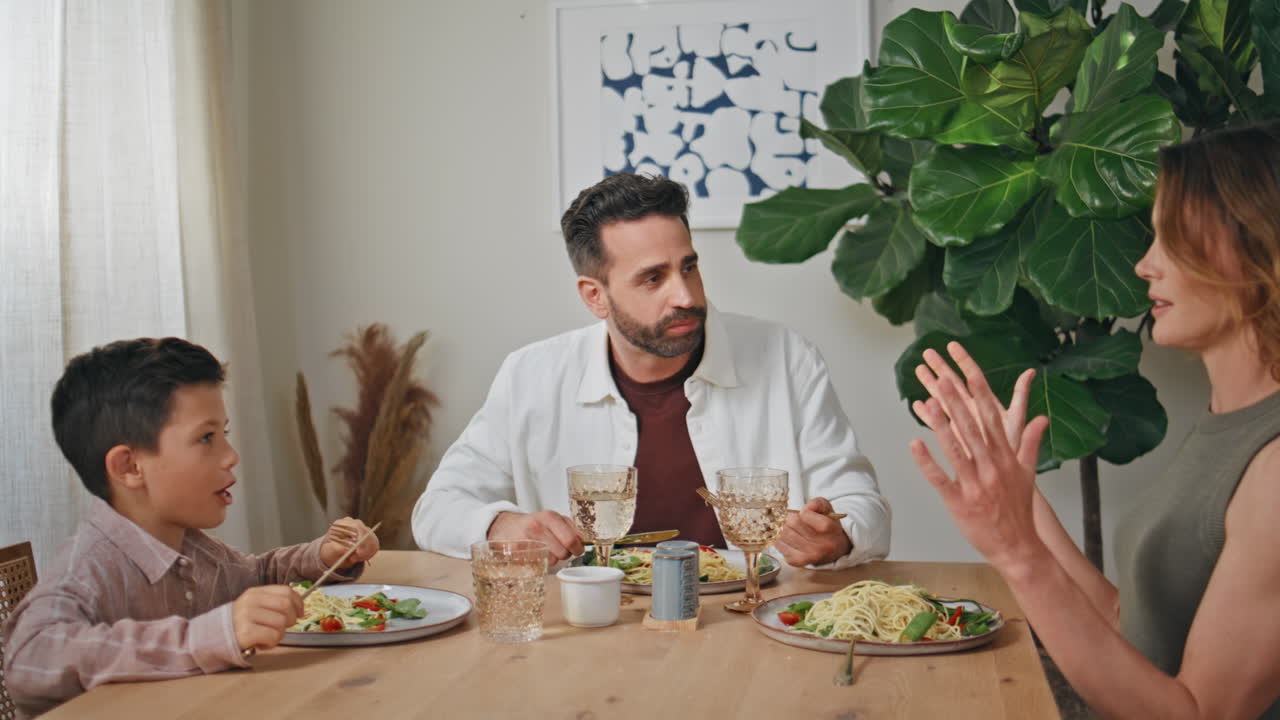 Talking parents kid eating at cozy kitchen closeup. Happy smiling family lunch