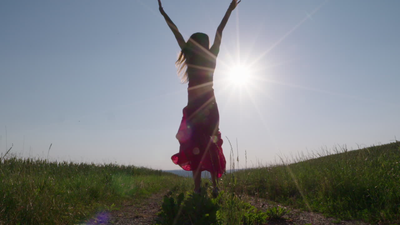 una mujer saltando en el aire frente al sol