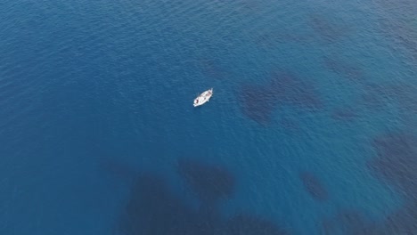 Lone-sailboat-is-crossing-the-crystal-blue-sea,-Pont-d'en-Gil,-Menorca