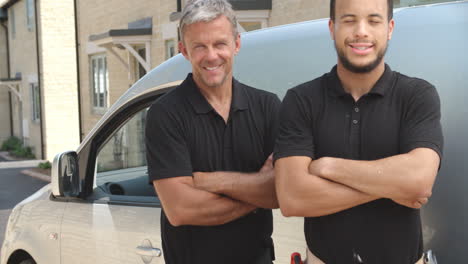 a young and a middle aged tradesman by van, panning up shot