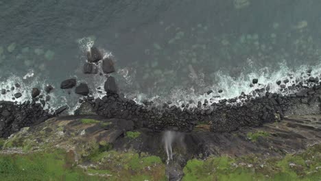 Drone-reveal-shot-of-a-waterfall-ending-in-a-sea-cliff-in-isle-of-skye-scotland