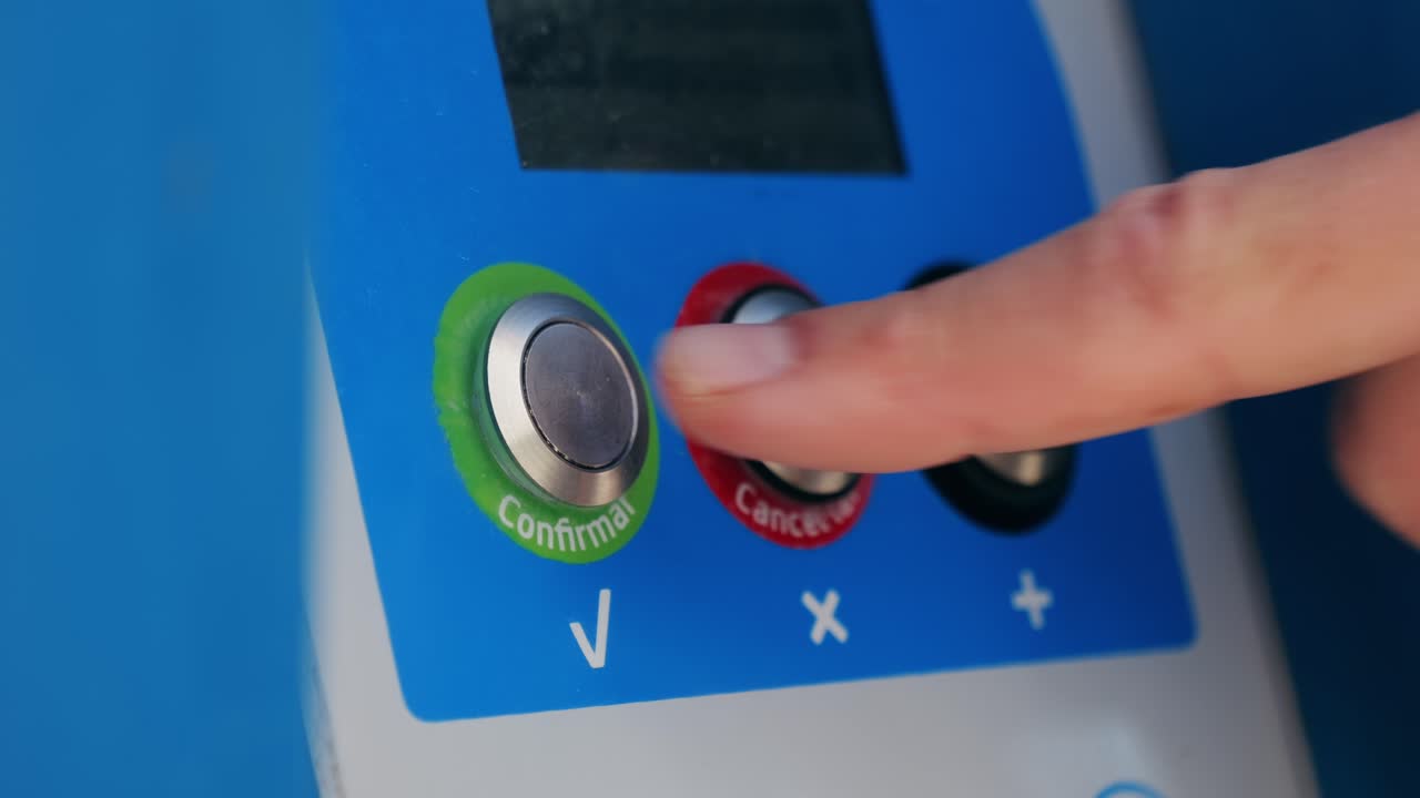 A finger pressing a confirmation button on a machine