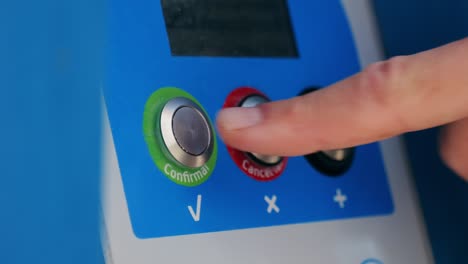 a finger pressing a confirmation button on a machine