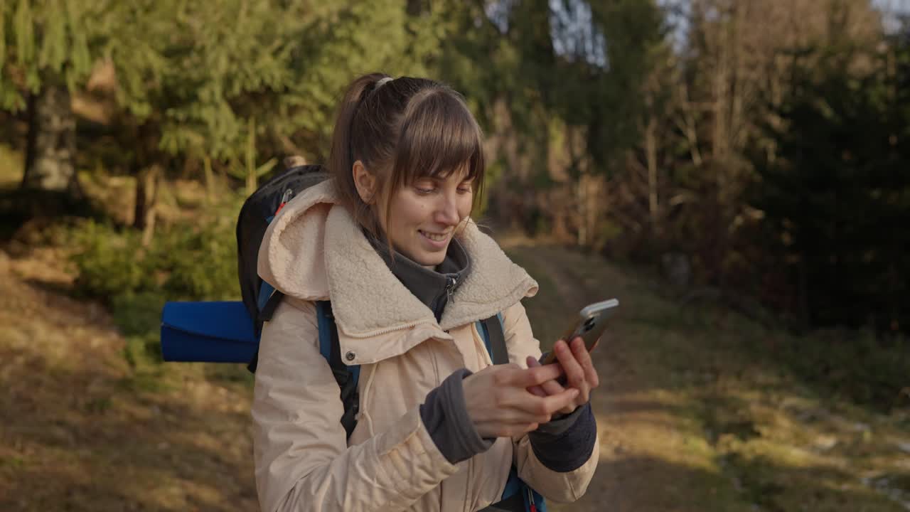 Woman with backpack taking a photo in forest