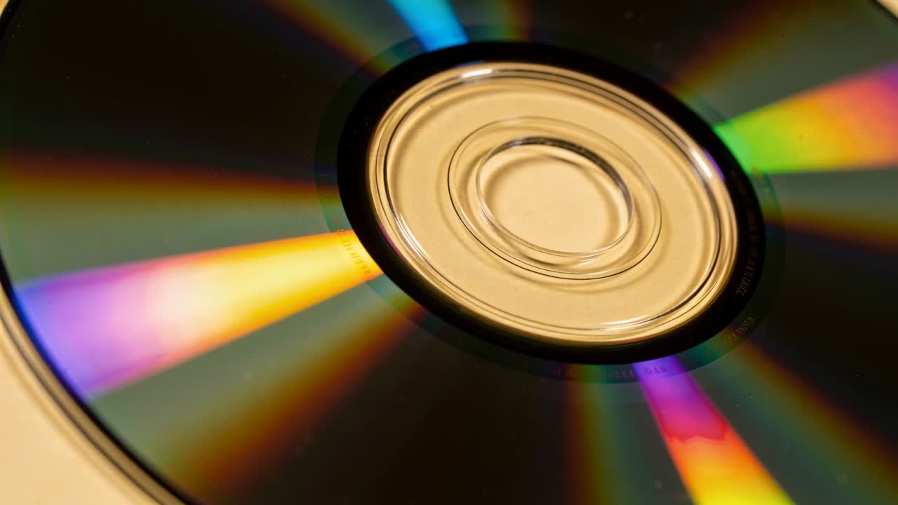 Roterende CD på en beige bordplate, med skiftende regnbuebånd nær sentralnavet.