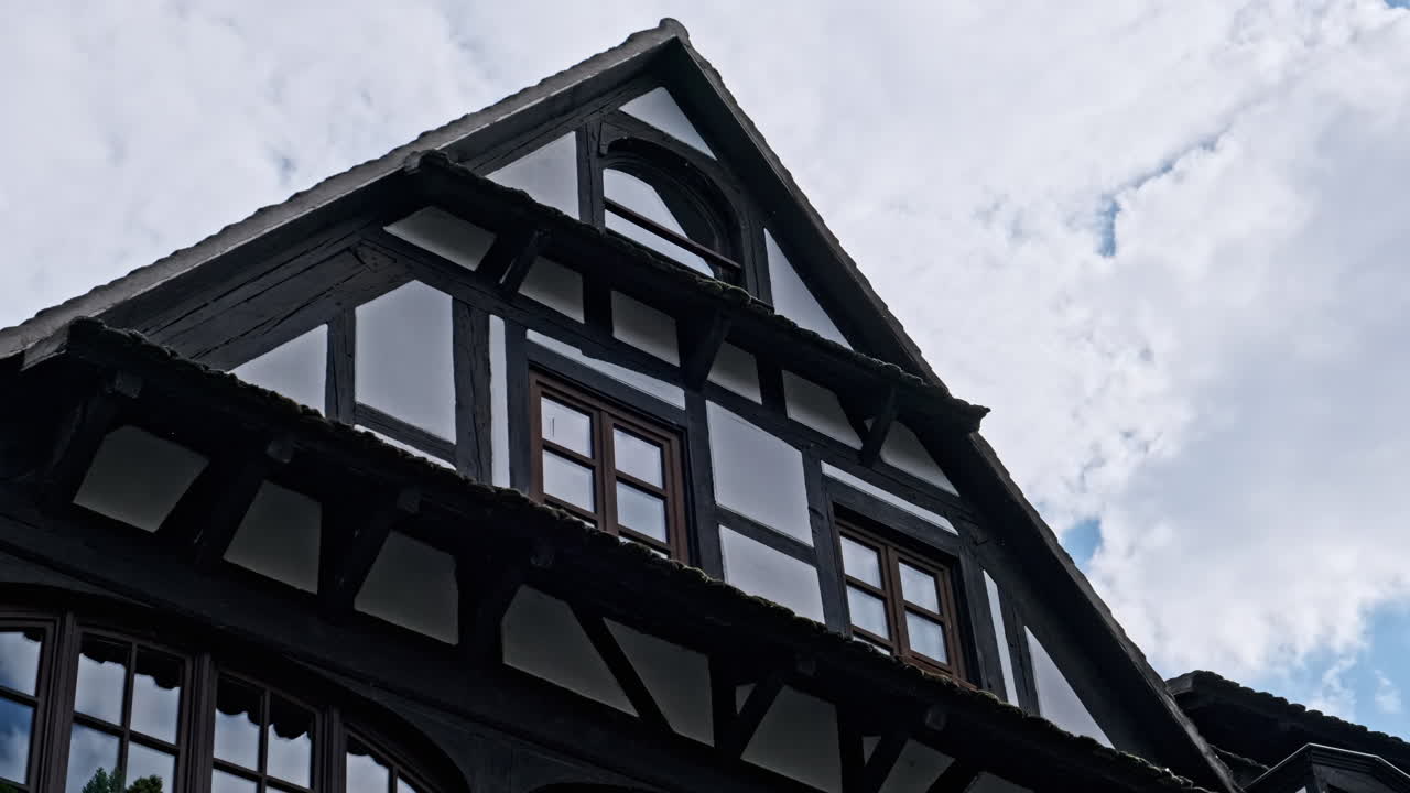 Upper part of a traditional half-timbered house against a cloudy sky