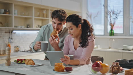 desayuno familiar mirando la tableta en la cocina. pareja navegando por internet en casa