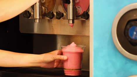 pouring a pink slushy into a cup