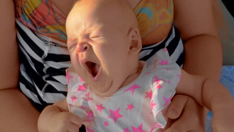 sleepy baby yawning when lying on mothers lap outdoor