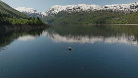 Kajakfahrer-Paddeln-Auf-Einem-Ruhigen-Bergsee-Mit-Schneebedeckten-Gipfeln-In-Røldal,-Norwegen