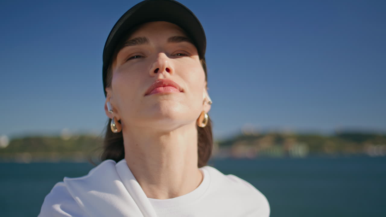 Closed eyes sportswoman stretching neck at sunny riverbank closeup. Active woman