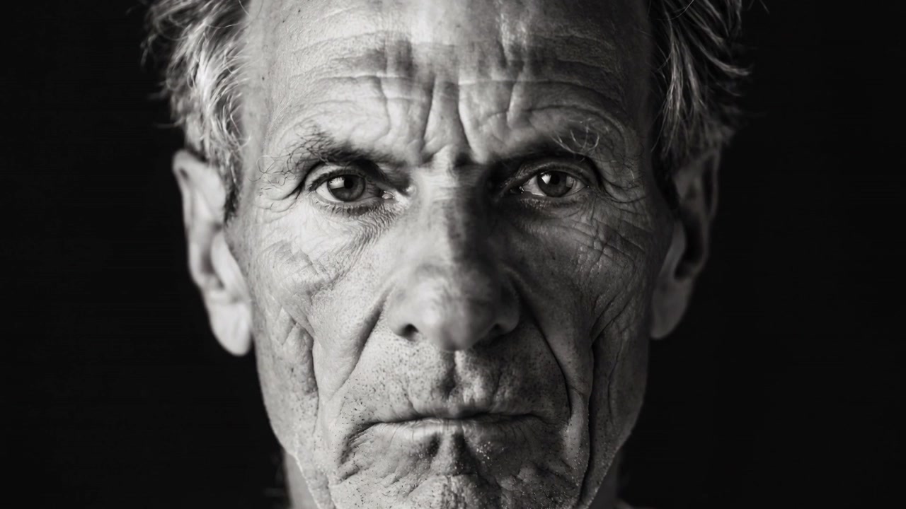 Inizio della registrazione, uomo anziano che mantiene uno sguardo fisso in uno studio fotografico per ritratti, mostrando la texture del viso.
