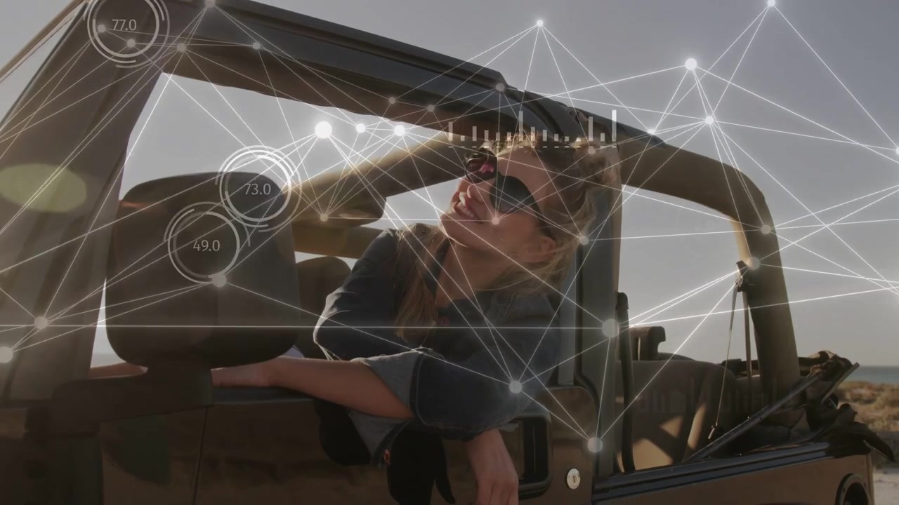 Donna passeggera che si sporge dalla portiera dell'auto, guardando l'orizzonte mentre la luce del sole si muove, animando grafici tecnologici HUD