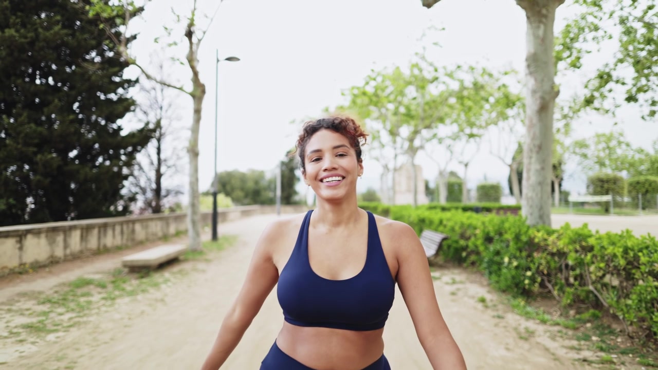 Donna atletica sorridente a passeggio in un parco verde