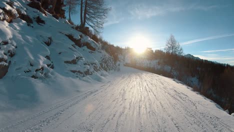 Going-down-a-snowy-pathway-at-sunset-with-snowboarders-further-ahead-and-turqoise-sky-above