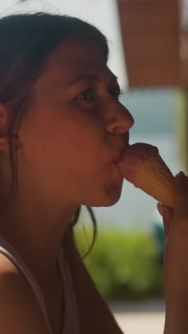 una mujer bonita disfruta del sabor del helado de frutas en un cono de obleas en una cafetería a cámara lenta. una mujer feliz come un helado saludable descansando en la terraza del restaurante