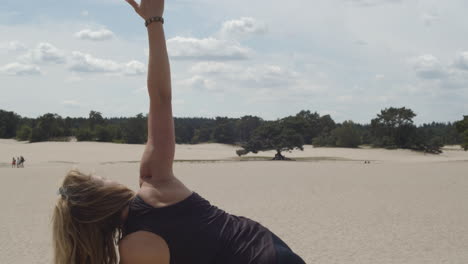 beautiful woman raising right arm while doing yoga exercises