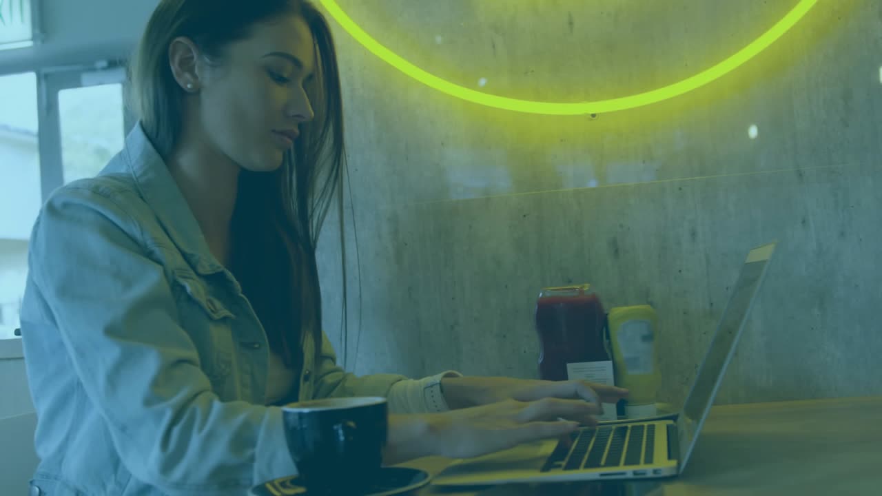 Woman typing on laptop in cafe, initiating numeric overlays over hands and cup, illustrating data